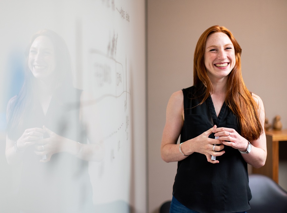 Woman smiling confidently beside a whiteboard